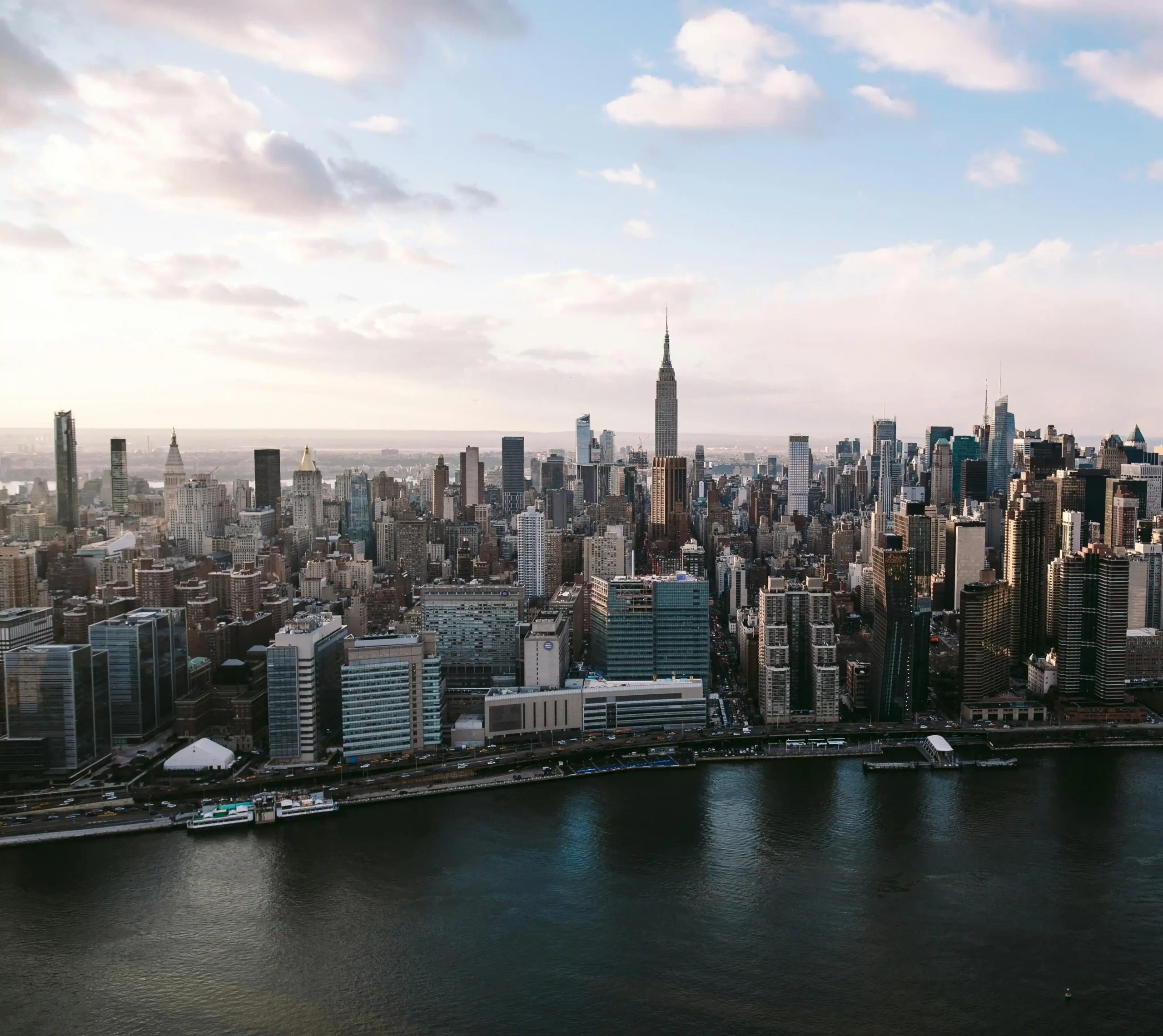 Aerial view of Manhattan skyline along the waterfront, showcasing dense urban real estate in a core investment market.